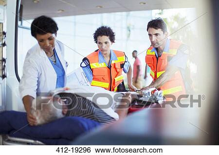 Stock Photograph - Paramedics and nurse examining patient in ambulance. Fotosearch
