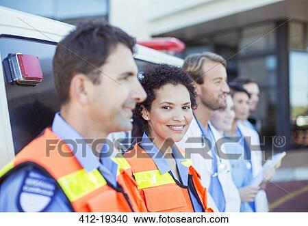 Stock Image - Paramedics, doctors and nurses smiling by ambulance. Fotosearch