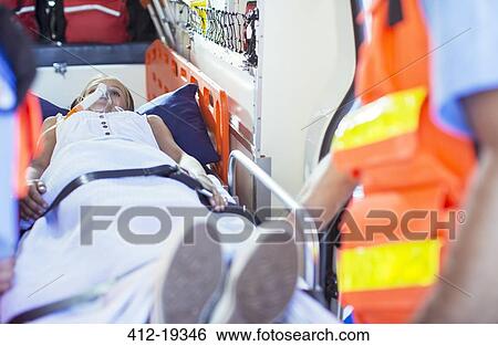 Stock Photograph - Paramedics examining patient on stretcher in ambulance. Fotosearch