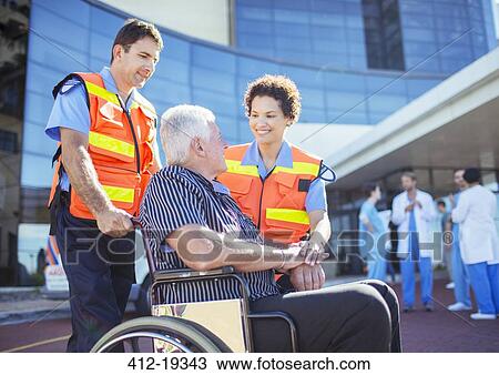 Stock Image - Paramedics talking to patient outside hospital. Fotosearch