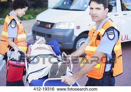 Stock Photograph - Paramedics wheeling patient on stretcher in hospital parking lot. Fotosearch