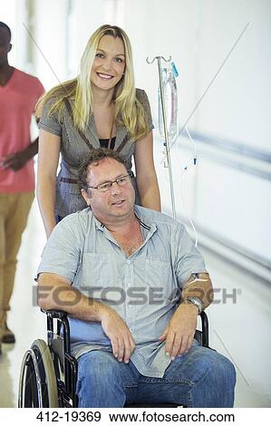 Woman wheeling father in hospital hallway View Large Photo Image Stock Photo - Woman wheeling father in hospital hallway. Fotosearch
