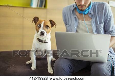Stock Photo - Dog sitting by man in office. Fotosearch
