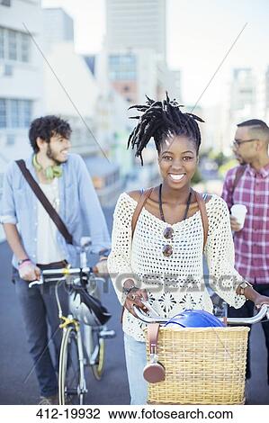 Friends pushing bicycles on city street View Large Photo Image Stock Image - Friends pushing bicycles on city street. Fotosearch