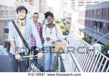 Stock Photo - Friends pushing bicycles on city street. Fotosearch