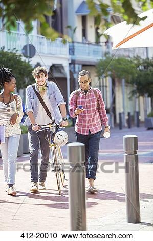 Stock Image - Friends walking together on city street. Fotosearch