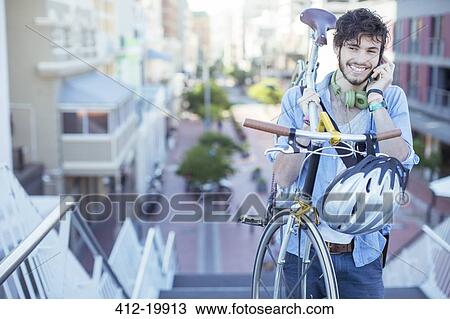 Stock Image - Man carrying bicycle on city steps. Fotosearch