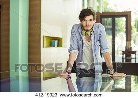 Stock Image - Man leaning on desk in office. Fotosearch