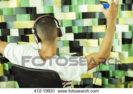 Man listening to mp3 player in armchair View Large Photo Image Stock Image - Man listening to mp3 player in armchair. Fotosearch