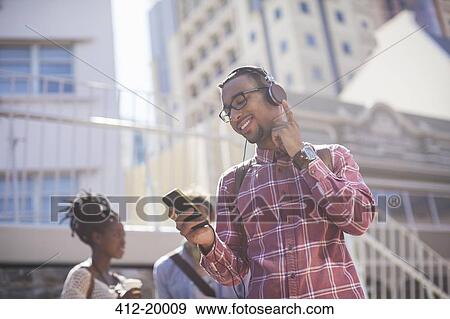 Stock Photo - Man listening to mp3 player outdoors. Fotosearch