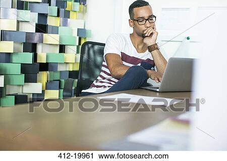 Stock Image - Man using laptop in office. Fotosearch
