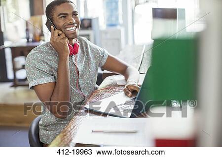 Stock Image - Man working at conference table in office. Fotosearch