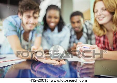 Stock Photography - People examining globe in office. Fotosearch
