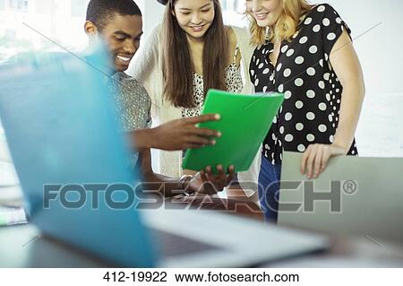 Stock Image - People using digital tablet together in office. Fotosearch