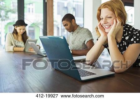 Stock Photo - People working on laptops in office. Fotosearch