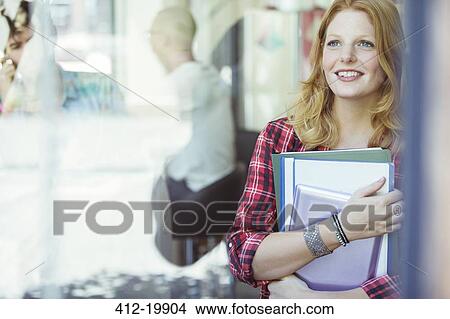 Picture - Woman carrying binders outdoors. Fotosearch