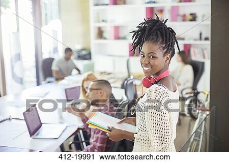 Stock Image - Woman carrying folders in office. Fotosearch