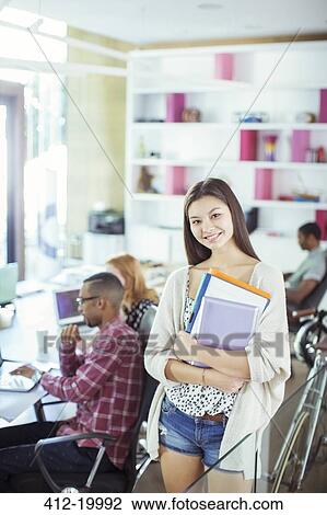 Woman carrying folders in office View Large Photo Image Stock Image - Woman carrying folders in office. Fotosearch