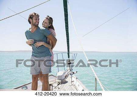 Stock Image - Couple hugging on deck of sailboat. Fotosearch