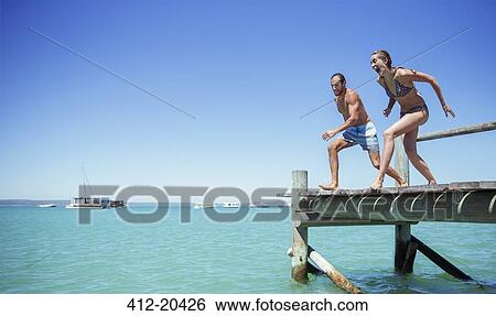 Couple jumping off wooden dock together View Large Photo Image Stock Photograph - Couple jumping off wooden dock together. Fotosearch