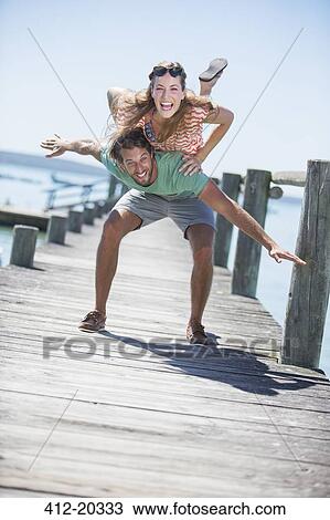Stock Image - Couple playing on wooden dock . Fotosearch