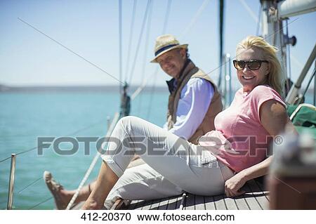 Stock Image - Couple relaxing on deck of sailboat. Fotosearch