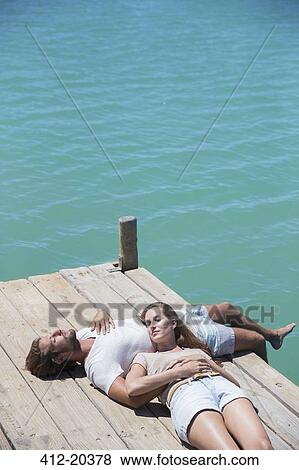 Couple relaxing together on wooden dock View Large Photo Image Stock Photo - Couple relaxing together on wooden dock . Fotosearch