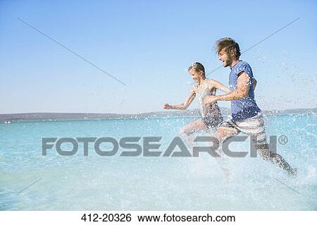 Couple running in water on beach View Large Photo Image Stock Photograph - Couple running in water on beach. Fotosearch