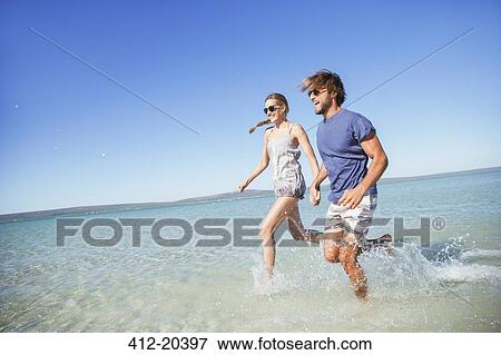 Stock Photo - Couple running in water together. Fotosearch