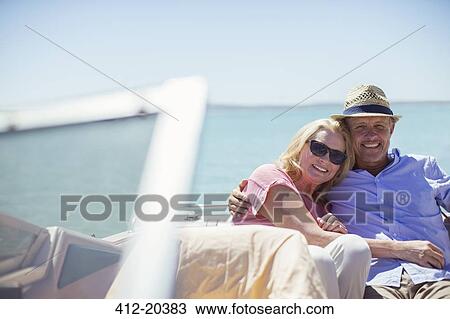 Stock Image - Couple sitting in boat on water. Fotosearch