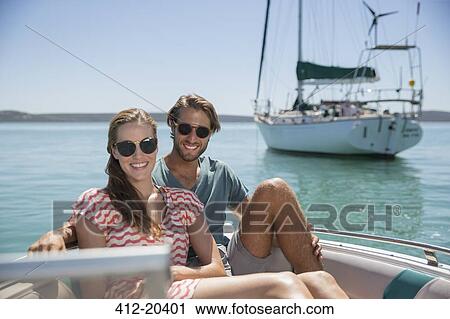 Stock Image - Couple sitting in boat on water. Fotosearch