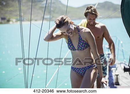 Couple standing on boat in water View Large Photo Image Stock Photograph - Couple standing on boat in water. Fotosearch