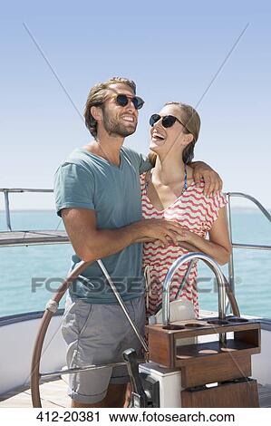 Stock Image - Couple steering boat together . Fotosearch