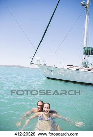 Couple swimming in water near boat View Large Photo Image Stock Photo - Couple swimming in water near boat . Fotosearch