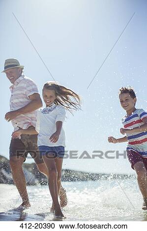 Family running in water on beach View Large Photo Image Stock Image - Family running in water on beach . Fotosearch