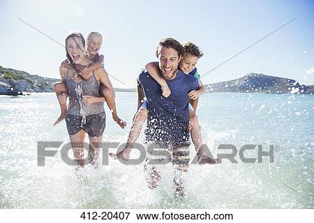 Stock Photo - Family running in water on beach. Fotosearch