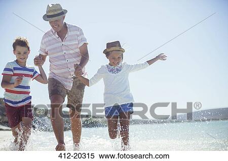 Stock Photography - Family running in water on beach . Fotosearch