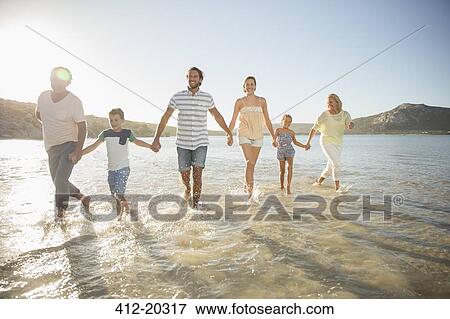 Family walking in shallow water on beach View Large Photo Image Stock Photo - Family walking in shallow water on beach . Fotosearch