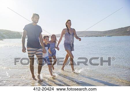 Picture - Family walking together along shore. Fotosearch