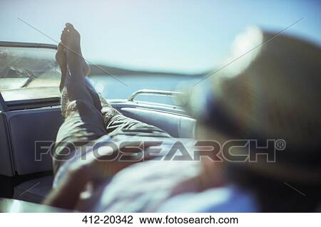 Stock Image - Man relaxing on boat near beach. Fotosearch