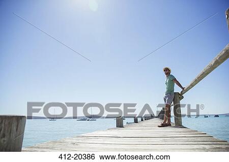 Stock Photograph - Man standing on wooden dock . Fotosearch