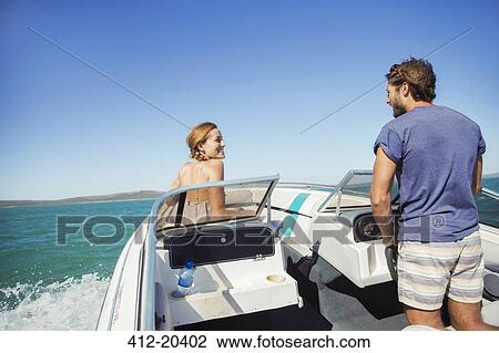 Stock Image - Man steering boat with girlfriend. Fotosearch