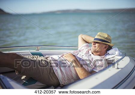 Stock Photo - Older man relaxing in boat on water . Fotosearch