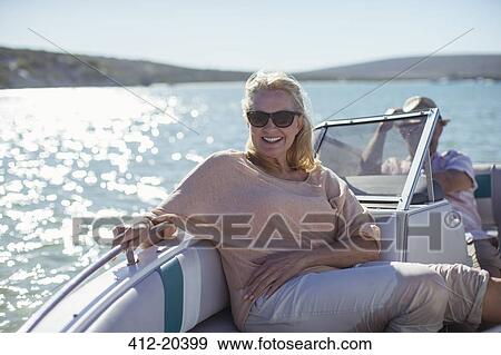 Stock Photo - Older woman sitting in boat on water. Fotosearch
