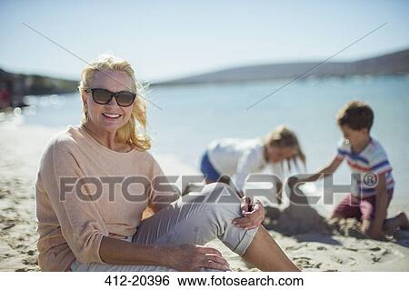 Older woman sitting on beach with family View Large Photo Image Stock Photograph - Older woman sitting on beach with family . Fotosearch