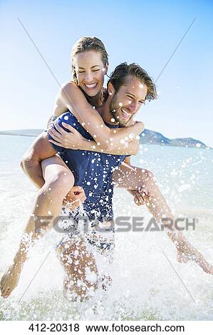 Woman riding piggy back on boyfriend in water View Large Photo Image Stock Photo - Woman riding piggy back on boyfriend in water. Fotosearch