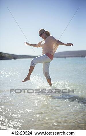 Picture - Woman splashing in water on beach . Fotosearch