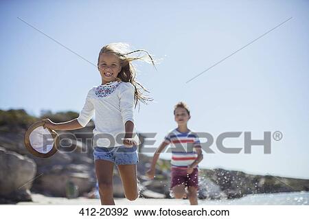 Young girl and boy running along beach View Large Photo Image Stock Image - Young girl and boy running along beach . Fotosearch