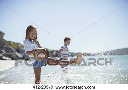 Stock Photo - Young girl splashing in water on beach. Fotosearch