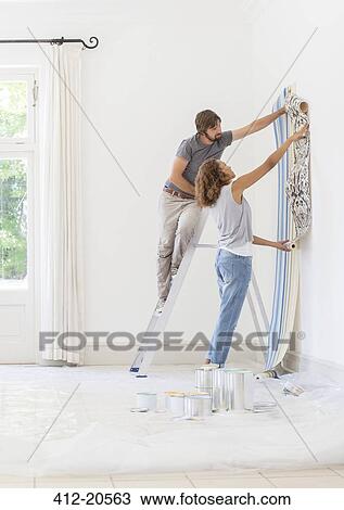 Stock Image - Couple hanging wallpaper together. Fotosearch